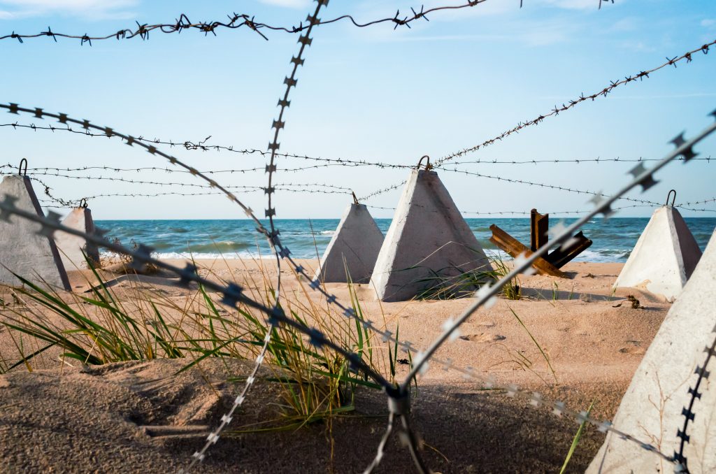 Barbed,Wire,And,Concrete,Military,Fence,On,The,Beach,Near